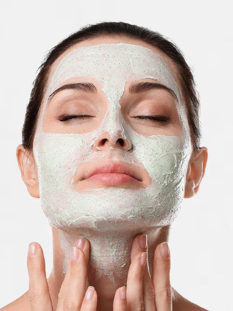 Woman applying a Golden Pearl Apple Glow Facial Scrub with a neutral background
