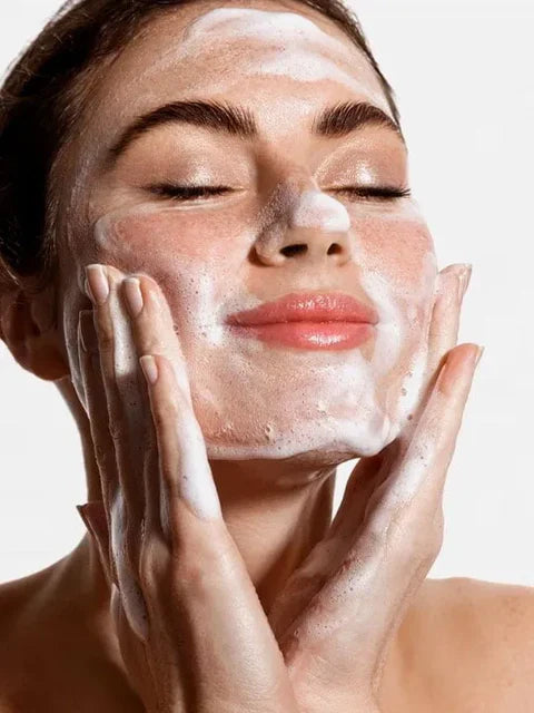 Woman applying Golden Pearl Flawless Face Wash  with her hands on a plain background