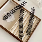 Set of black hair curlers in a wooden box on a white background