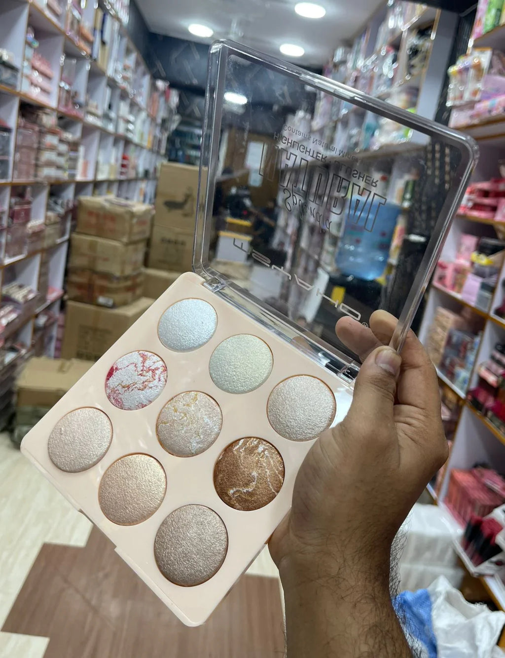 Makeup palette with colorful shades held by a hand in a store setting